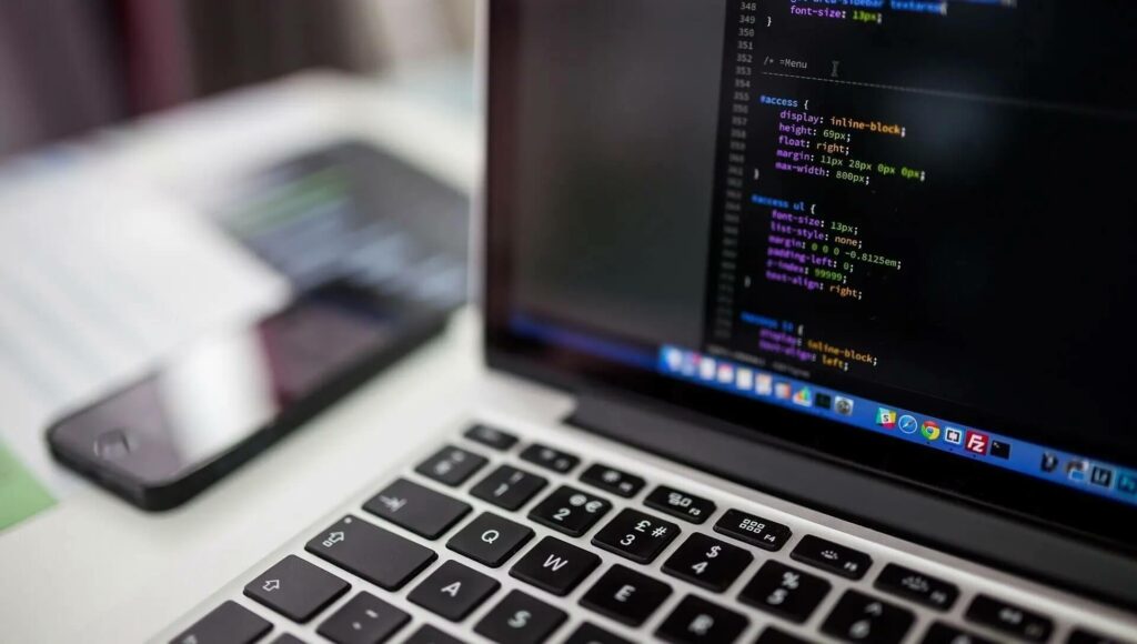 Laptop-Bildschirm mit css-Code, daneben liegt ein Handy