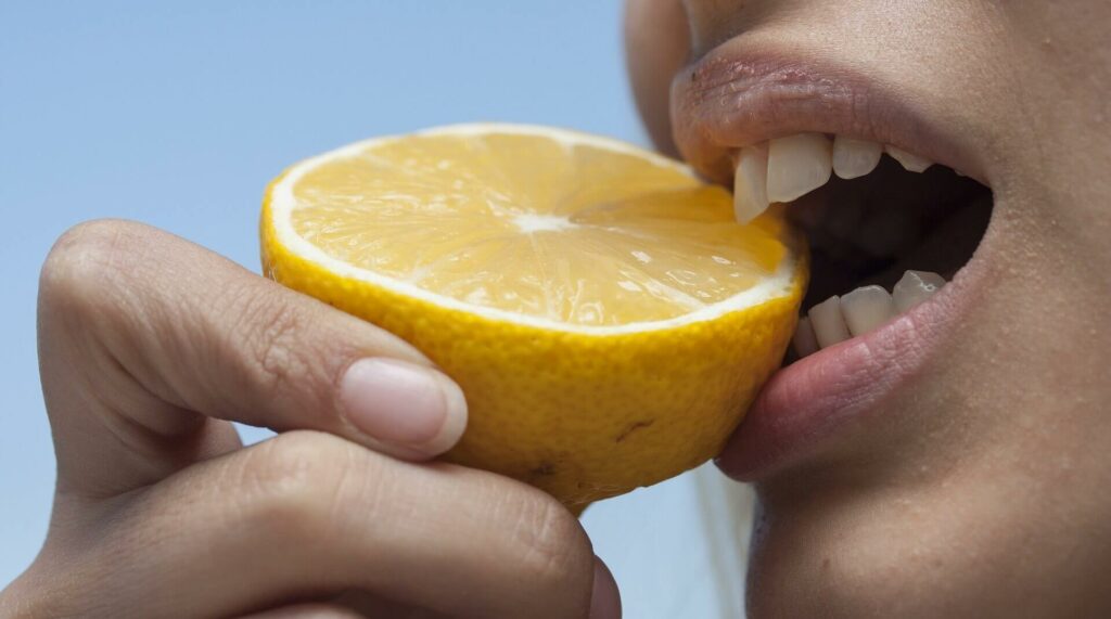 Frau beißt in Zitrone