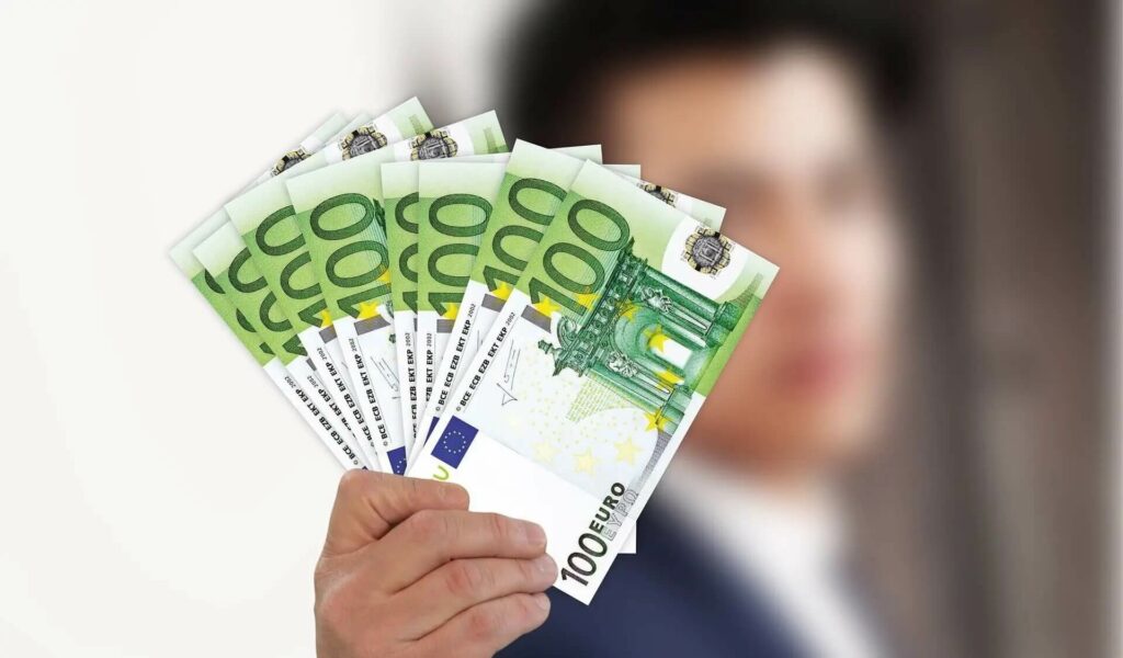 Subventionsbetrug Corona (Symbolbild) - Person hält Bündel 100 €-Scheine